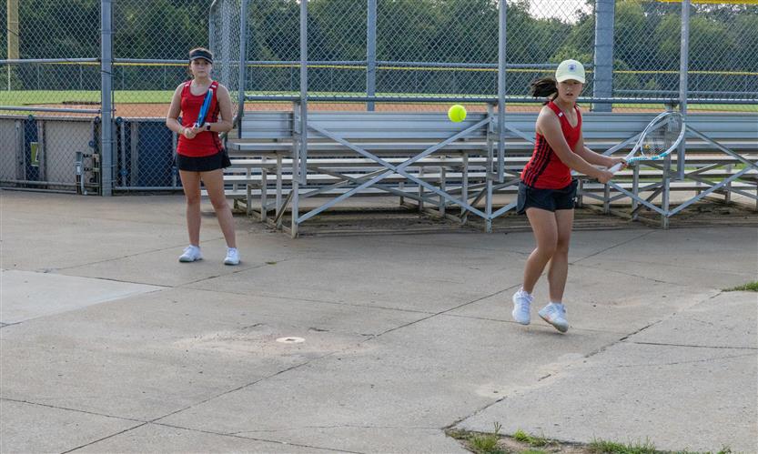 Two tennis players practice before a match